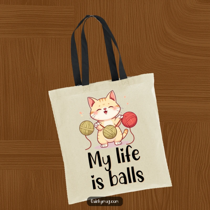Funny tote bag with a mischievous cat juggling three yarn balls, ideal for carrying supplies for crafters and cat enthusiasts.